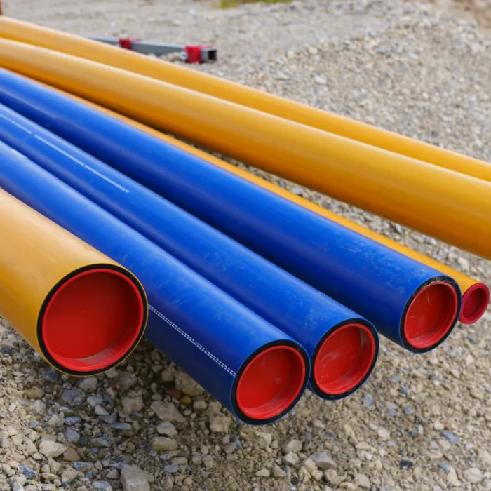 HDPE conduit in orange and blue sitting on gravel
