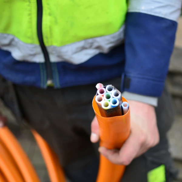 Construction worker holding HDPE multi-duct orange conduit on job site